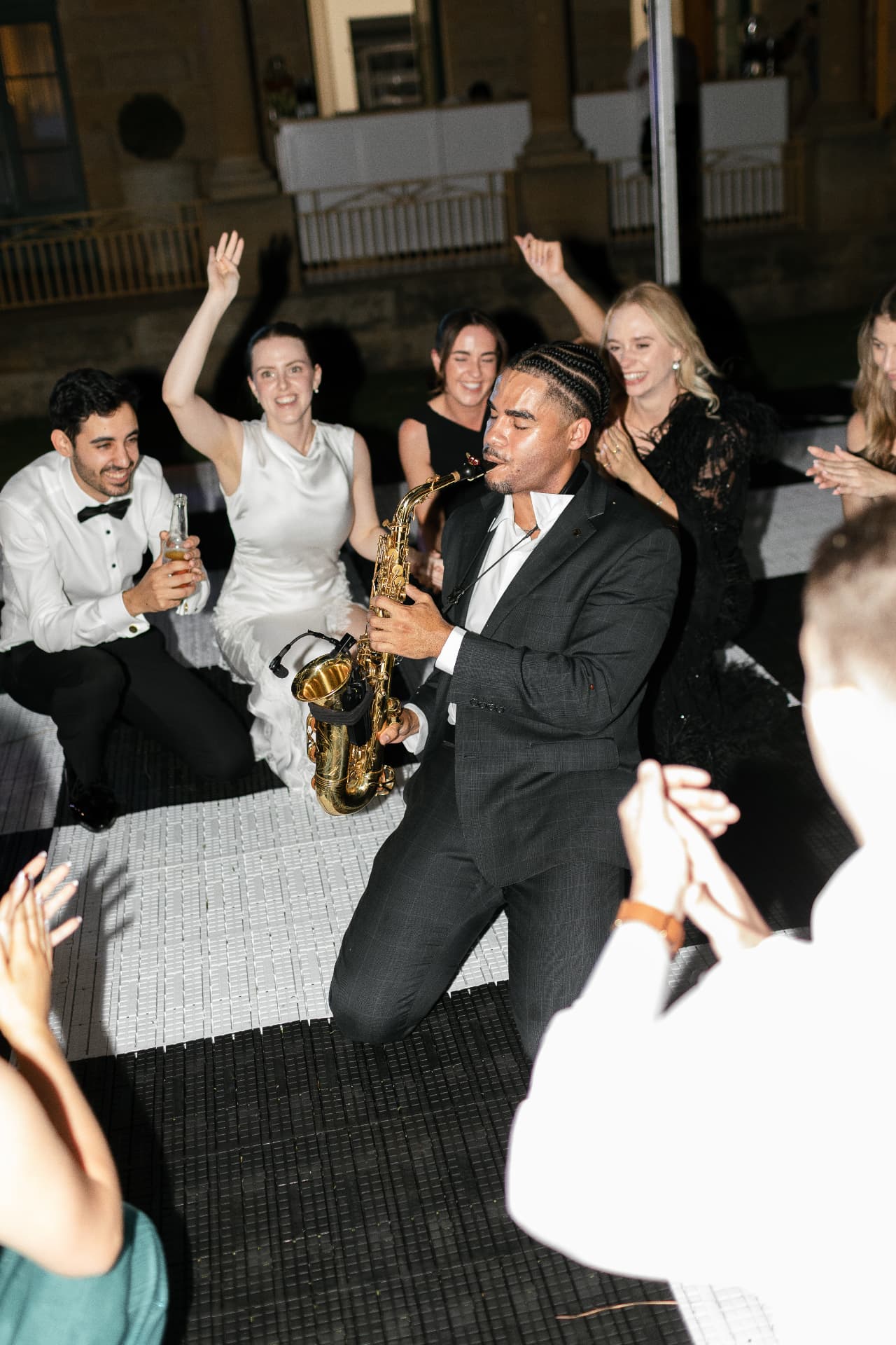 Kneeling saxophone solo surrounded by cheering guests
